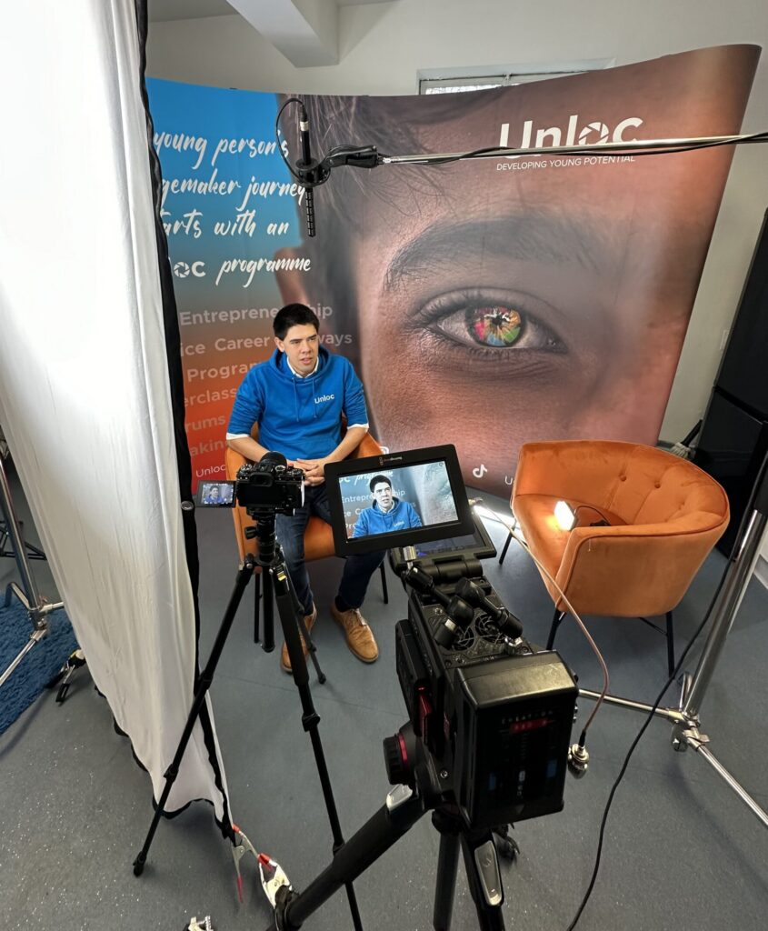 man in front of banner giving interview